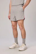 Men's light grey athletic shorts with pink trim, paired with grey socks and white sneakers