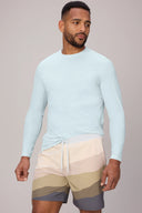 Man wearing light blue long sleeve UV swim shirt and earth-tone swim shorts