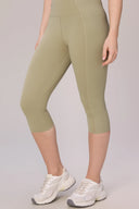 Woman wearing high-waisted sage green compression capri leggings, white sneakers