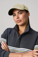 Woman wearing light khaki baseball cap and half-zip striped athletic pullover