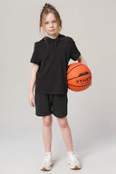 Girl in charcoal hooded athletic tee and shorts holding basketball, studio background