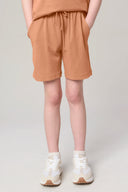 Girl wearing mocha brown athleisure shorts with drawstring and pockets, casual white sneakers