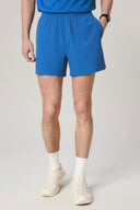 Man wearing cobalt blue athletic shorts with elastic waistband, white socks, and sneakers