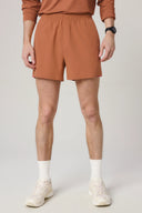 Man wearing dark suntan athletic shorts and sneakers, casual activewear look