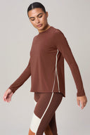Woman wearing sepia brown long sleeve athletic sweater with cream side stripes and matching leggings