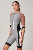 Woman wearing colorblock rashguard athletic romper with zip front and neutral tones