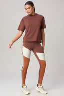 Woman wearing a loose-fit brown short sleeve top and colorblock brown leggings for activewear
