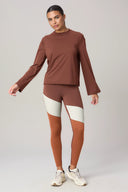Woman wearing brown loose fit long sleeve top and colorblock leggings, athleisure outfit
