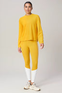 Woman wearing mustard yellow long sleeve top and yellow leggings with white panels