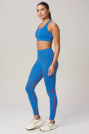 Woman wearing cobalt blue high-waisted leggings and sports bra with red seam details