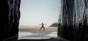 Woman in activewear doing yoga pose on a sandy beach between two rock cliffs