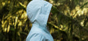 Person in white hooded jacket standing in a forest, outdoor activewear, side profile