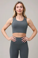 Woman wearing grey athleisure sports bra and high-waisted leggings, hands on hips