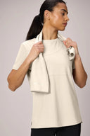 Woman wearing sand-colored performance t-shirt holding a matching towel, athleisure apparel