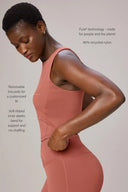 Woman wearing a burnt amber compression bra and leggings, highlighting soft elastic band and removable pads, made from 80% recycled nylon.