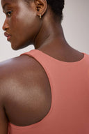 Close-up of woman wearing burnt amber racerback sports bra, focus on fabric texture and fit