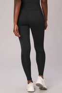 Back view of woman wearing charcoal compression leggings with mesh panels and white sneakers