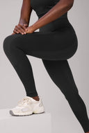 Woman wearing charcoal compression leggings with mesh side panels and white sneakers