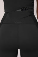 Close-up of charcoal high-waisted compression leggings with mesh panels and phone pocket