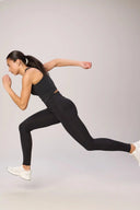 Woman running in charcoal compression bra and leggings, athleisure activewear set