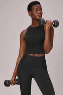 Woman in black mesh compression sports bra and high-waisted leggings lifting dumbbells