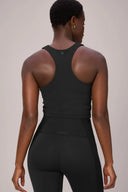 Woman wearing charcoal mesh compression sports bra and high-waisted leggings, back view