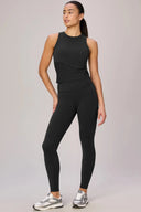 Woman modeling high-waisted charcoal compression leggings and sleeveless top, athletic wear