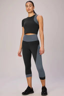 Woman wearing cropped black and charcoal gray performance tee and matching leggings