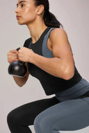 Woman in charcoal performance tee and leggings holding kettlebell in fitness pose