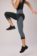 Woman wearing charcoal and granite color-blocked cropped leggings in active pose