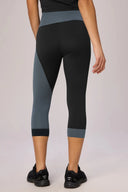 Back view of woman wearing color-blocked cropped leggings in charcoal and granite tones