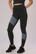 Woman wearing charcoal and granite color block high-waisted leggings, activewear style