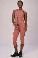 Woman in burnt amber seamless compression crop top and leggings holding a jump rope