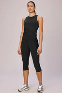 Woman wearing charcoal compression athletic crop top and capri leggings, studio setting