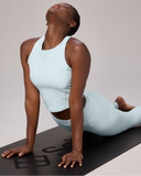 Woman in light blue PFAS-free athleisure doing yoga in upward dog pose on black mat