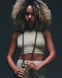 Woman in light green athleisure set holding jump rope, sporty activewear look