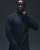 Man wearing a black zip-up athleisure jacket in a studio setting