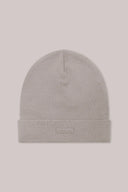 Light beige knit beanie hat with a folded cuff and subtle label, on a plain background