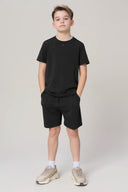 Boy wearing charcoal basic tee and black shorts, athletic style, neutral background