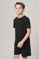 Boy wearing charcoal short sleeve basic tee and matching shorts on light background