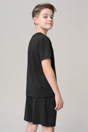 Boy wearing charcoal short-sleeve tee and shorts set, turned to the side, on plain background