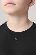 Close-up of child wearing charcoal crew neck activewear t-shirt with subtle chest logo