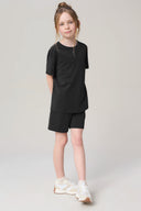 Girl wearing charcoal short sleeve athletic tee and matching shorts, white sneakers