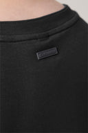 Close-up of charcoal black basic tee collar with small brand patch on back neck