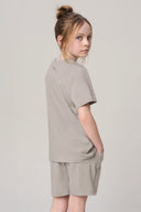 Girl wearing driftwood beige basic tee and shorts, side view, athleisure outfit