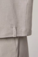 Close-up of driftwood beige cotton tee shirt hem with fabric tag and matching pants