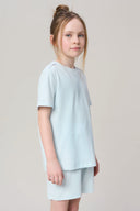 Girl wearing light blue basic tee and shorts, casual athleisure outfit on neutral background