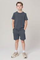 Boy wearing granite grey athletic t-shirt and shorts set, casual sneakers, neutral background