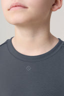 Close-up of a boy wearing a granite gray crewneck athleisure tee with small logo
