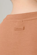 Close-up of mocha brown crew neck T-shirt with small embossed logo patch on the back neckline.